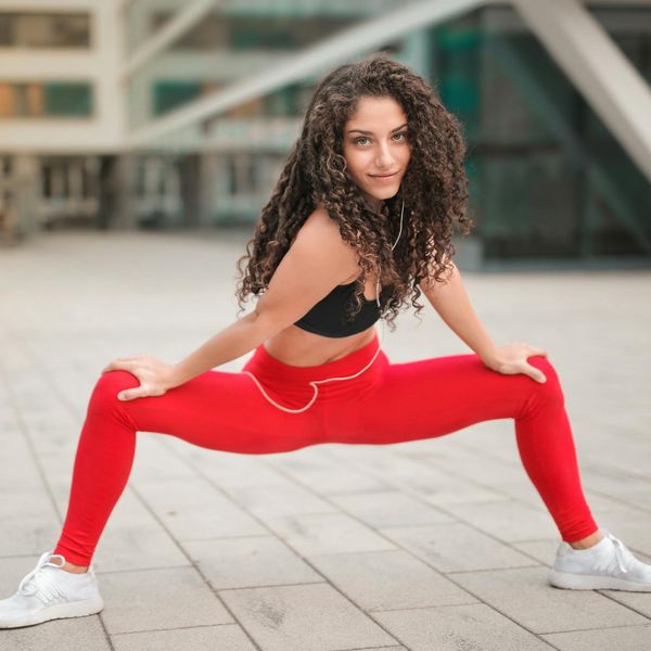 A woman smiling and stretching outdoors, looking full of energy and vitality.